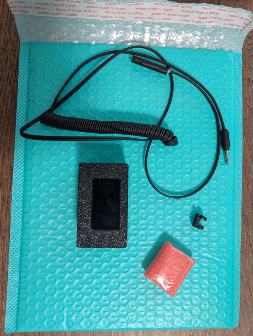 The Collidera kit laid out: receiver with LCD screen, wheel sensor with cable and audio jack, sensor holder, and the magnet in red bubble wrap